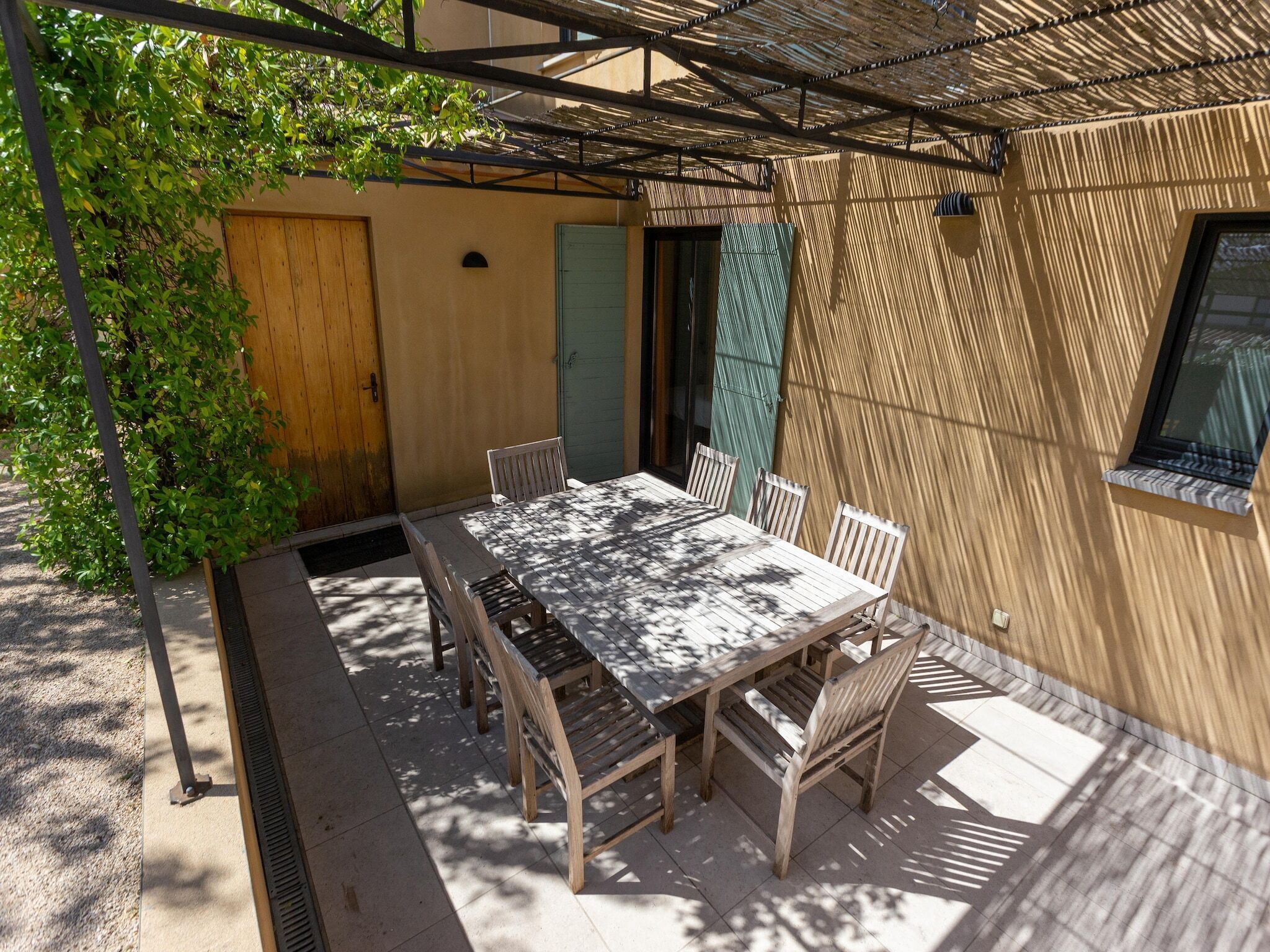 Un patio couvert avec une table et des chaises, une porte en bois et une fenêtre.