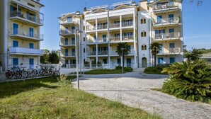 Un edifici d'apartaments de diversos pisos amb balcons, un pati empedrat i bicicletes aparcades a l'exterior.