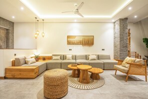 A modern living room with a sectional sofa, a wooden coffee table, and a rattan ottoman. - Coastal Comfort: Cozy 4BR Villa, 5 Min Walk to Finns Beach (Canggu)