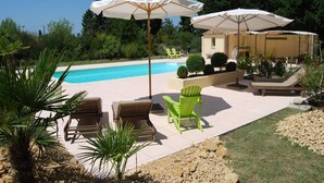 Ein Poolbereich mit Schwimmbecken, Liegestühlen und Sonnenschirmen.