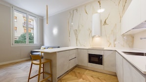 A modern kitchen with a marble backsplash, built-in oven, and a large window.