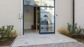 A modern entrance with a sliding glass door, a small outdoor seating area, and a mailbox.