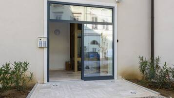 Un ingresso moderno con porta scorrevole in vetro, una piccola area salotto esterna e una cassetta delle lettere.