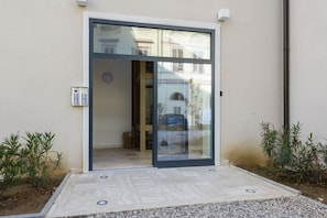 A modern entrance with a sliding glass door, a small outdoor seating area, and a mailbox.