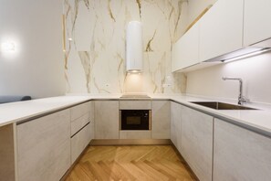 A modern kitchen with marble backsplash, built-in oven, and stainless steel sink.