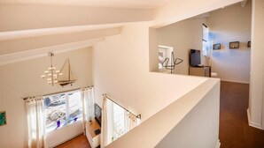 A modern interior with a staircase leading to a second floor, a dining area with a table and chairs, and a view of the outside through a window. - 06V - Beautiful villa with spa, pool and tennis (Biot)