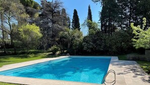 A rectangular swimming pool with a clear blue water, surrounded by a paved deck and a grassy area. - 06V - Beautiful villa with spa, pool and tennis (Biot)