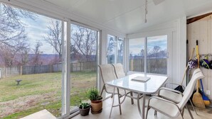 Et solrum med glasdør, et bord, stole og en potteplante.