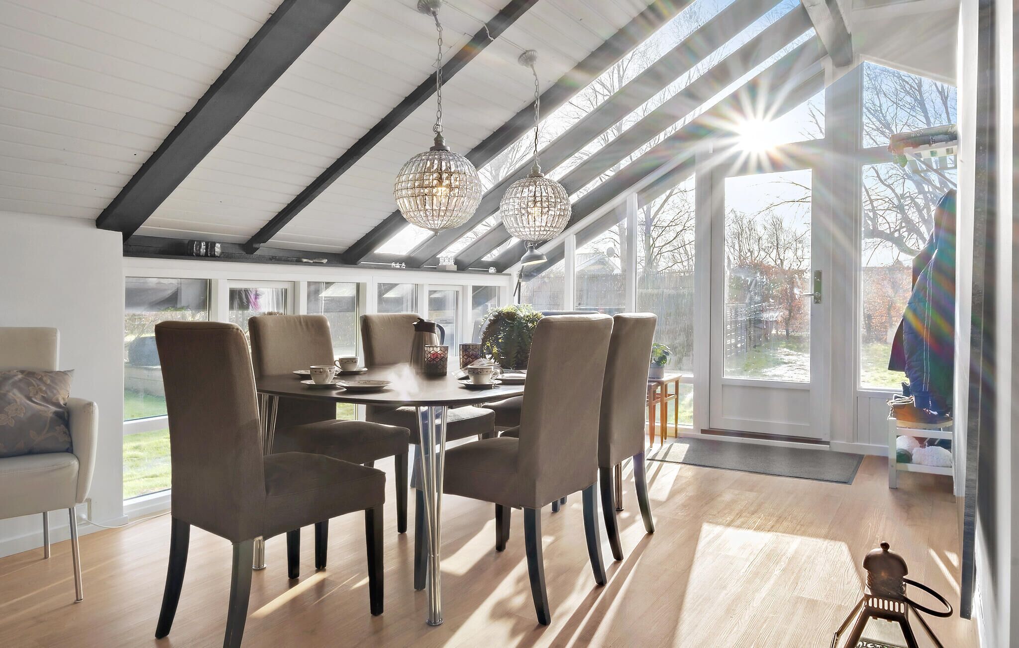 A modern dining room with a high ceiling, large windows, and a view of the outdoors.