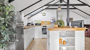 A modern kitchen with white cabinetry, a wooden countertop, and a built-in oven. There is a dining area with a wooden table and chairs, and a large window providing natural light. - Lovely home in Hadsund with WiFi (Hadsund)