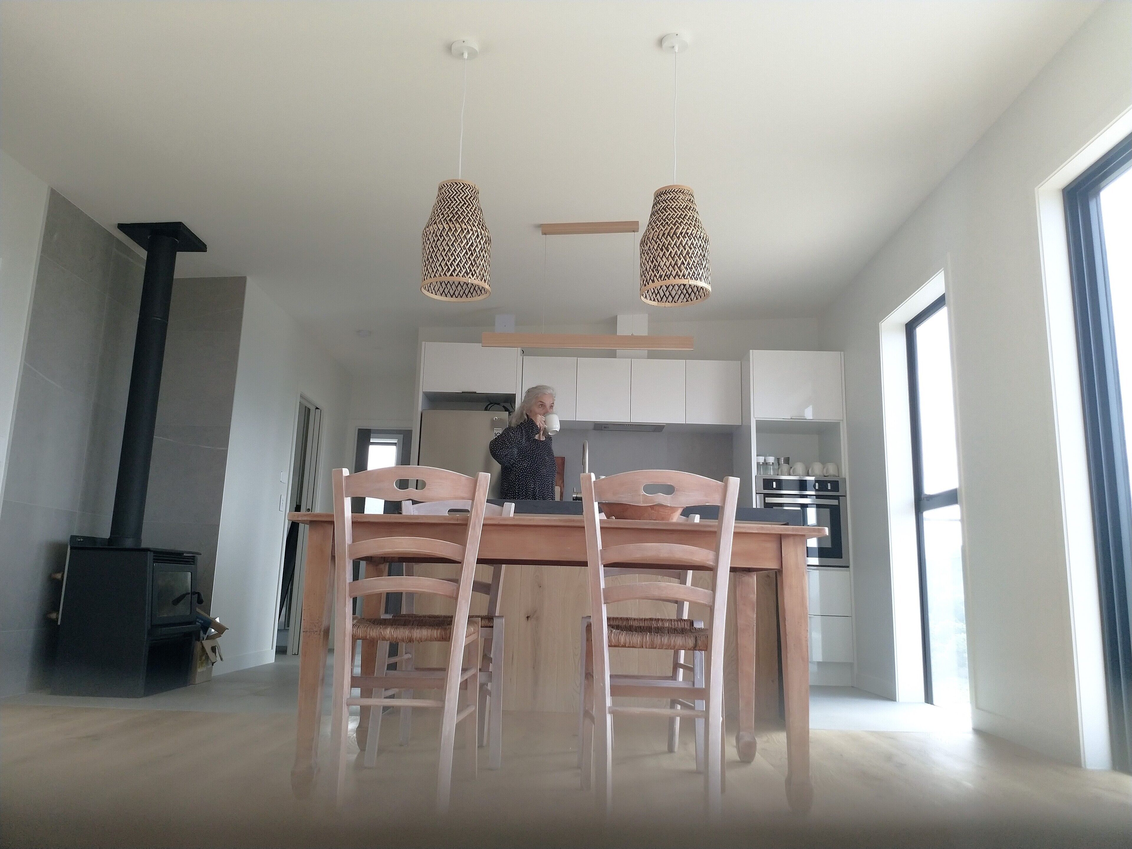 Een moderne keuken met houten kastjes, een eettafel met stoelen en hanglampen.