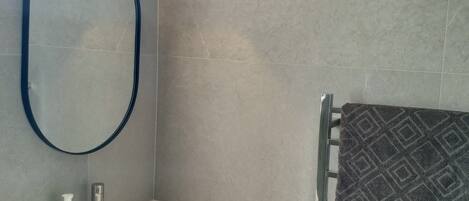 A bathroom with a white sink, a mirror, a towel rack with a patterned towel, and a wall-mounted light.