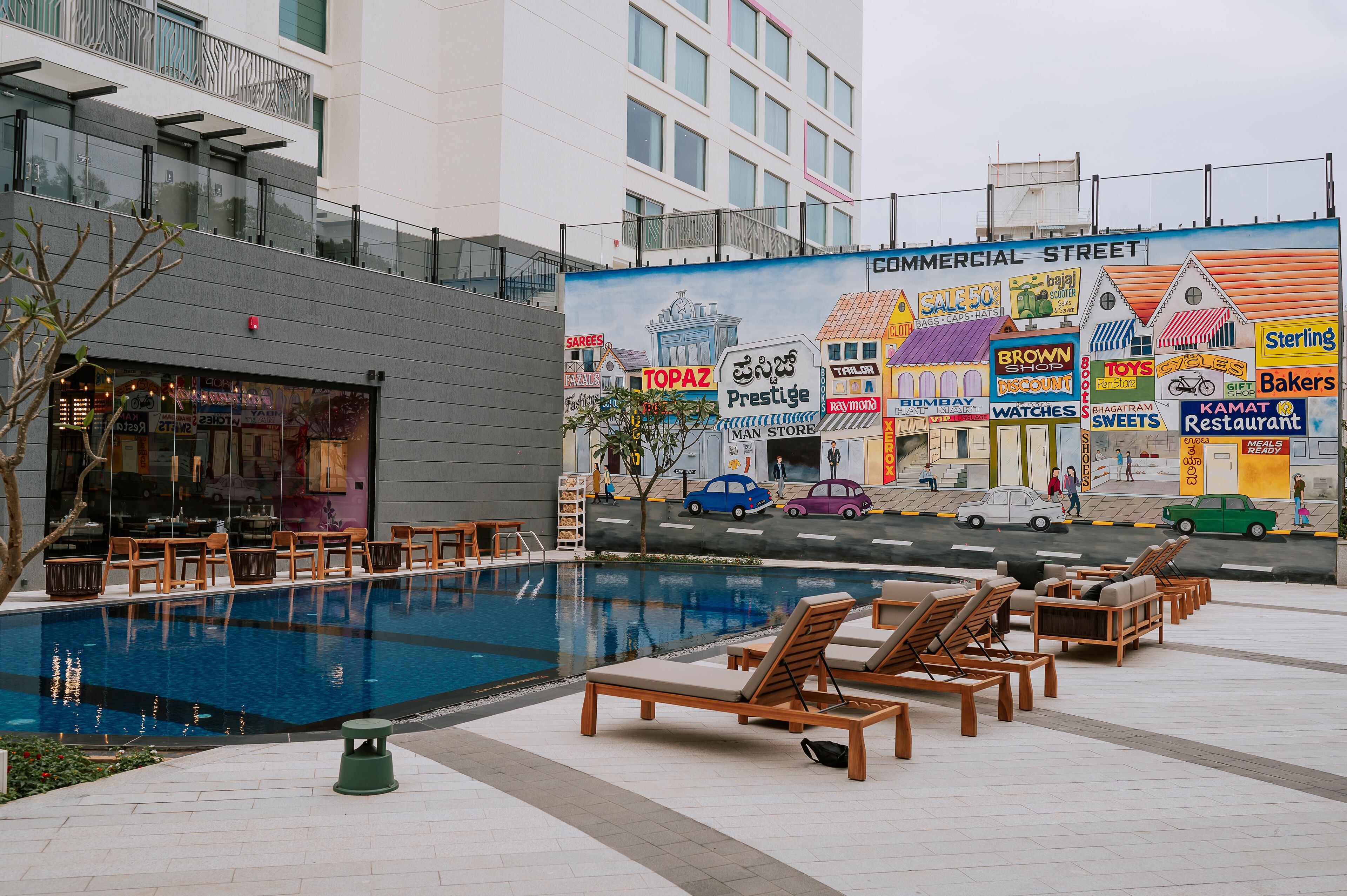 A pool area with lounge chairs and a restaurant.