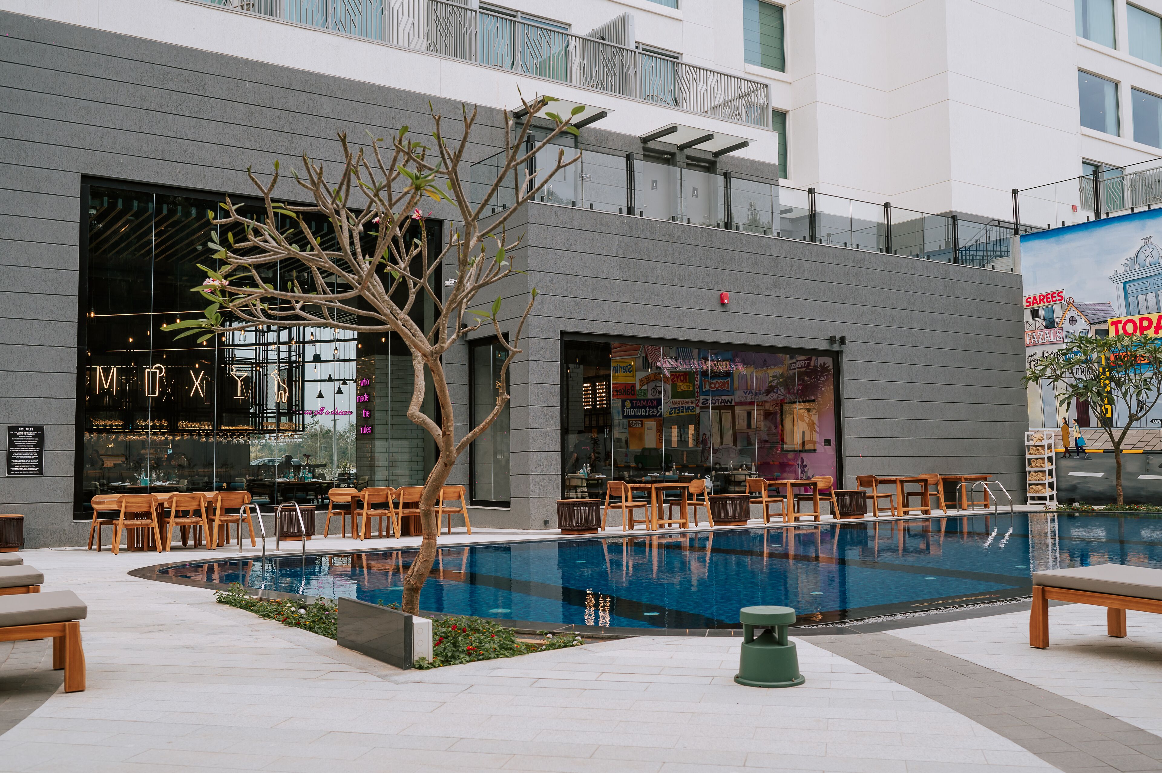A modern building with a pool, outdoor seating, and a restaurant.