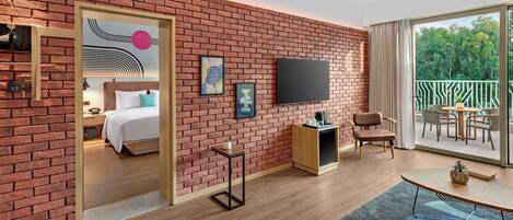 A modern hotel room with a brick wall, a bed, a TV, a balcony, and a dining area.