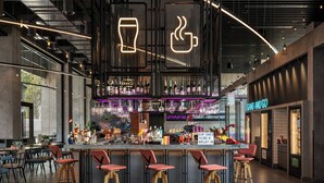 Un espace bar moderne avec un comptoir, des tabourets et un panneau néon.