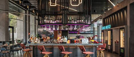 A modern bar area with a bar counter, stools, and a neon sign.