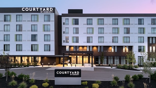 Un hotel Courtyard by Marriott con diseño moderno, que cuenta con un patio central y varios pisos con grandes ventanales.