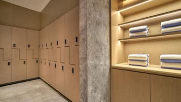 Une salle de bain moderne avec des casiers en bois, une colonne en marbre et des serviettes soigneusement pliées, rangées sur des étagères.