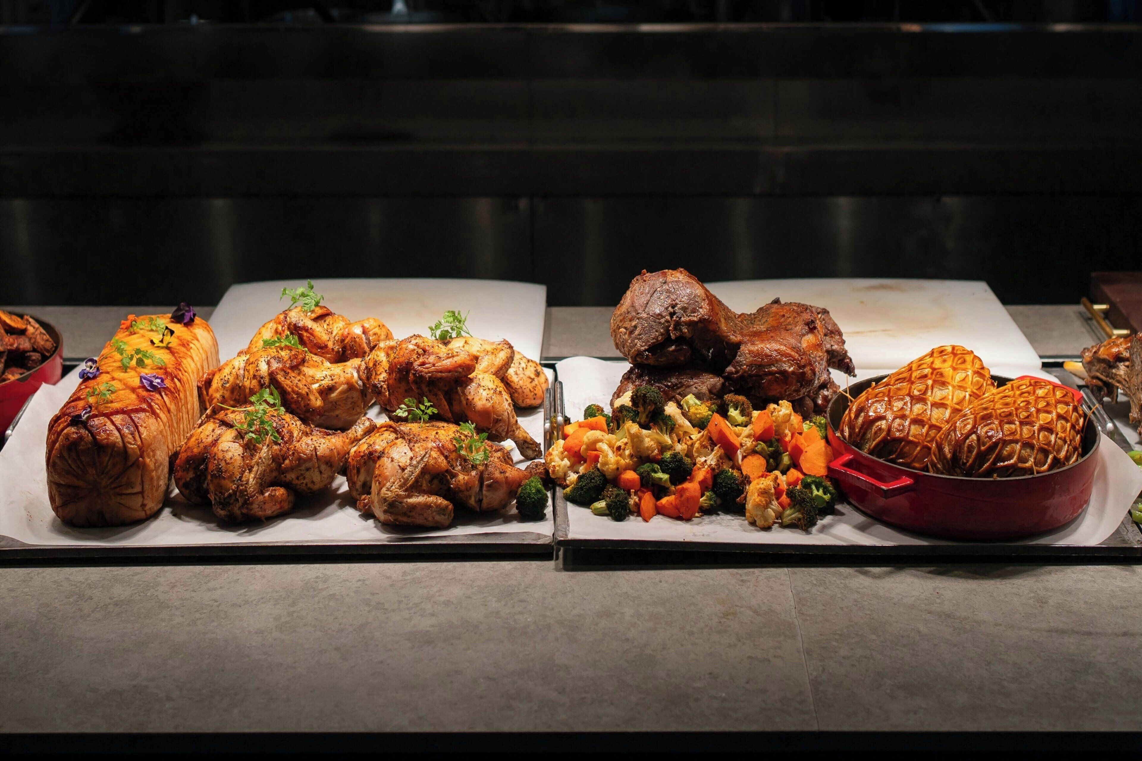 A buffet with various dishes including roasted meats, vegetables, and a whole roasted chicken.