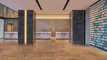 A spacious lobby with marble flooring, a reception desk, and a decorative wall with a mosaic pattern.