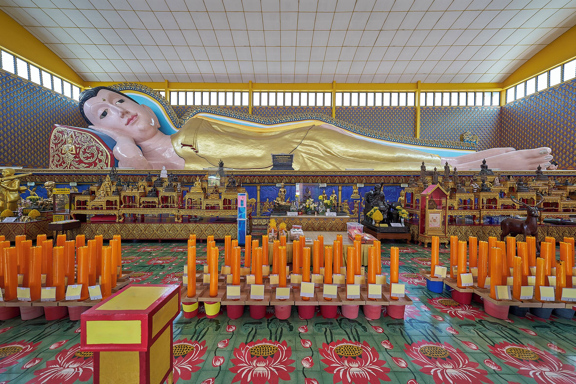 A large hall with a golden statue, rows of candles, and intricate wall patterns.