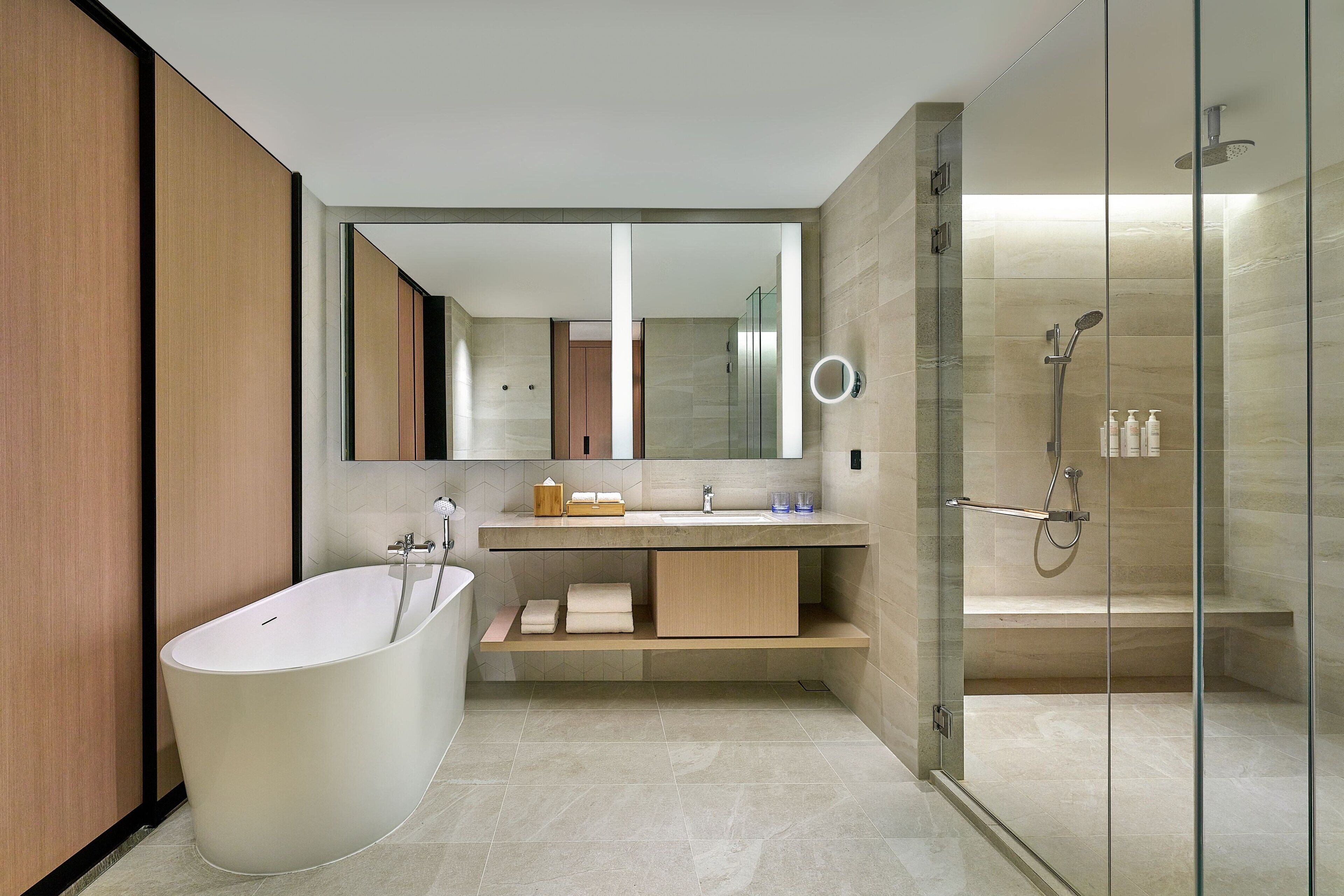 A modern bathroom with a freestanding bathtub, a glass-enclosed shower, and a vanity with a mirror.