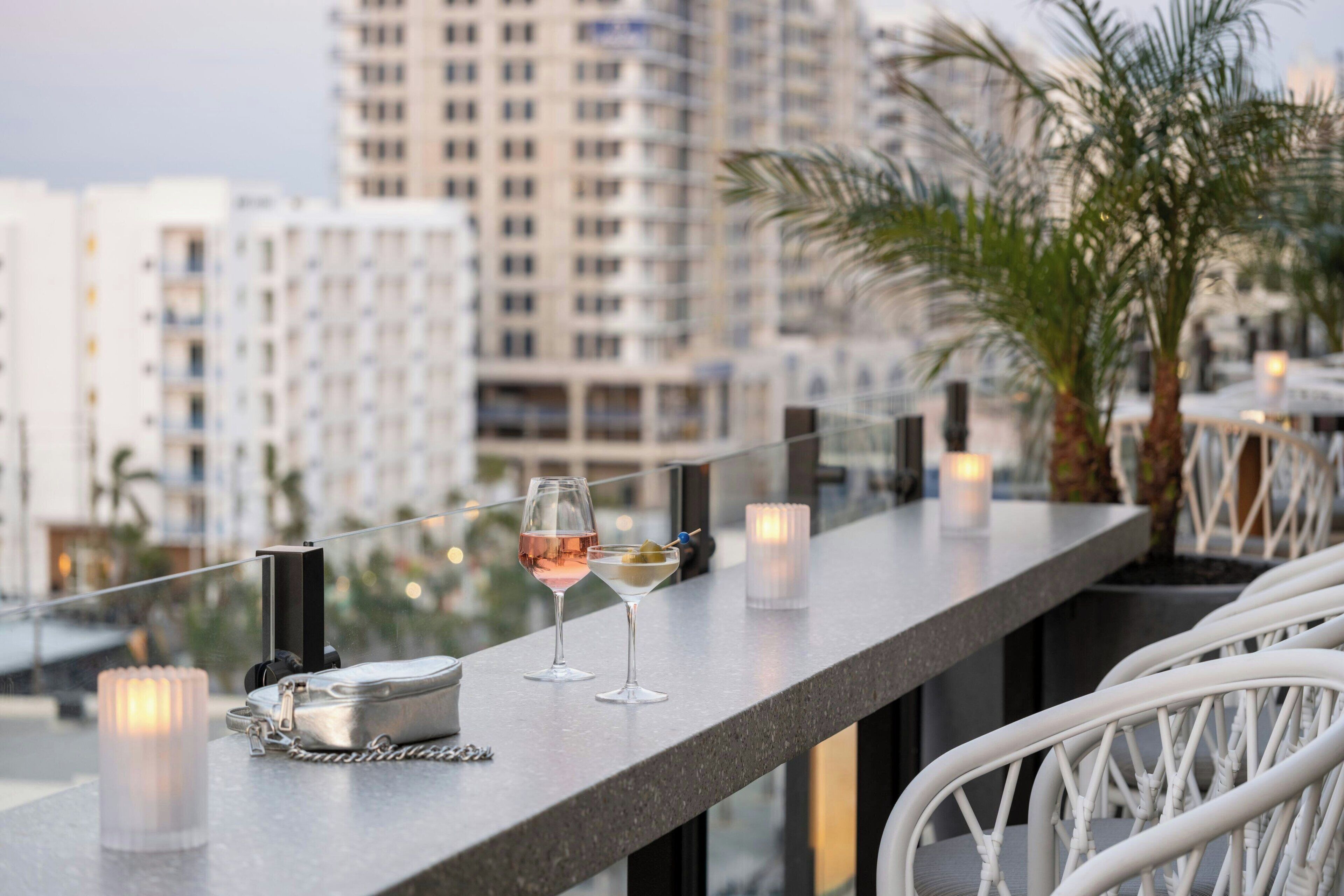 A balcony with a table set for two, featuring a cocktail glass and a candle.