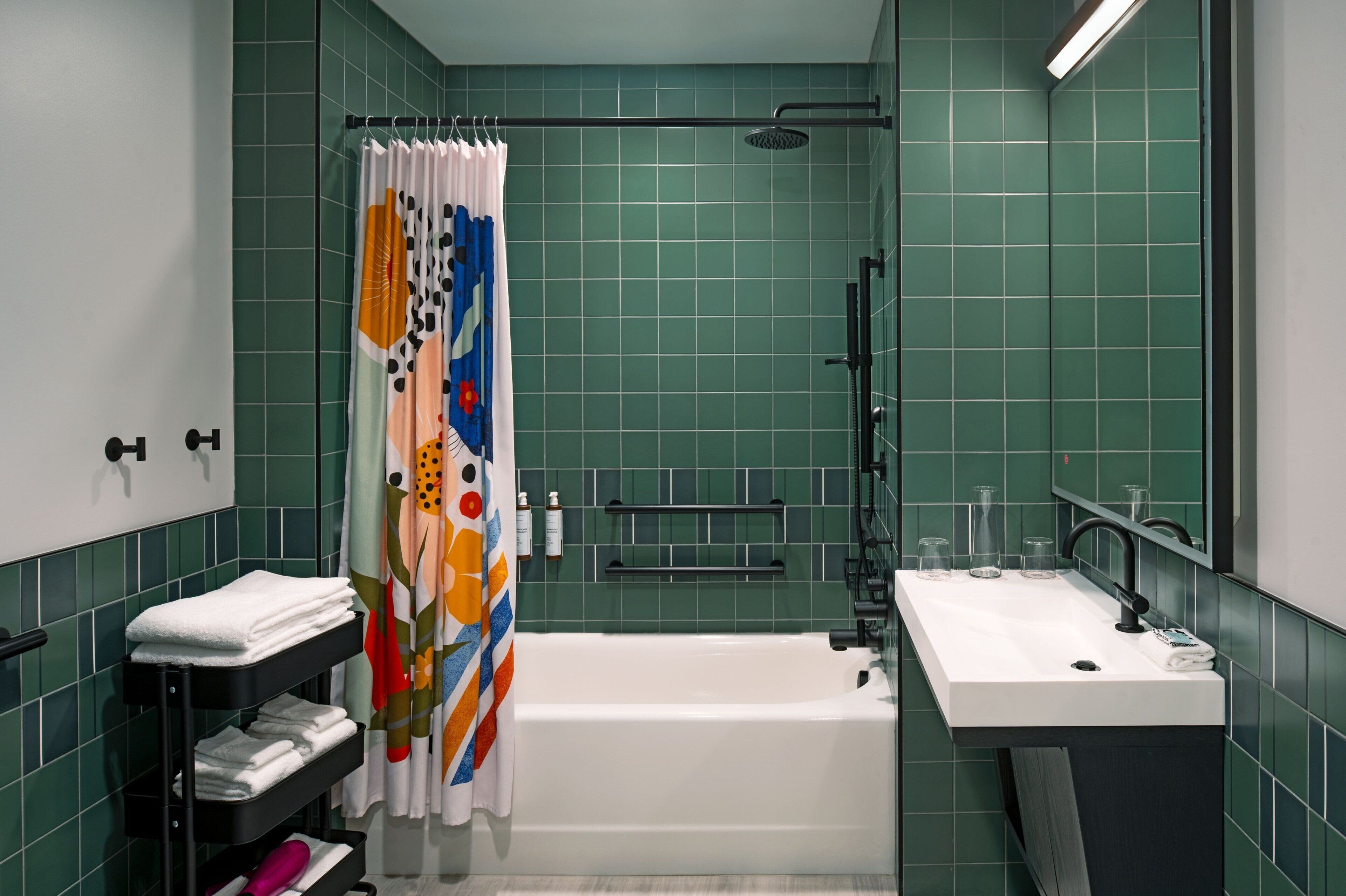 A bathroom with a white bathtub, a sink with a mirror, and a shower area.
