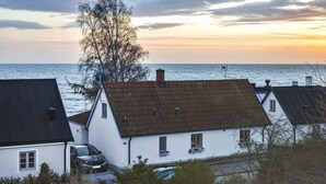 A coastal residential area with white houses, a tree, and a view of the sea at sunset. - 3 bedroom stunning home in Ystad (Ystad)