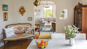 A cozy living room with a floral sofa, a wooden cabinet, and a dining table with a fruit bowl. - 3 bedroom stunning home in Ystad (Ystad)