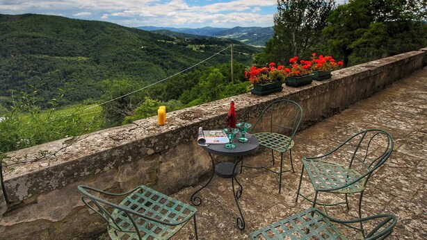 Terraza con mesa y sillas con vistas a un paisaje montañoso.