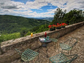 Een terras met tafel en stoelen met uitzicht op een bergachtig landschap.