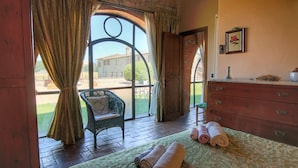 A room with a bed, a chair, a dresser, and a window with curtains. - Cottage in Todi with Pool and Terrace (Todi)