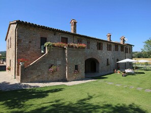 A stone building with a courtyard, featuring a covered outdoor seating area with umbrellas. - Charmante Escape in Todi (Todi)