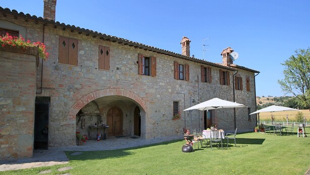 Un bâtiment en pierre doté d’une cour, d’un espace extérieur aménagé pour s’asseoir et d’une pelouse.