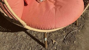 A wicker chair with a round cushion and multiple pillows in shades of red and beige. - Luxury home, minutes from MSU campus (Starkville)