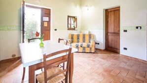 Ein Essbereich mit Tisch und Stühlen, einer gemusterten Couch, einer Holzzahlende und einer Tür mit Fenster.