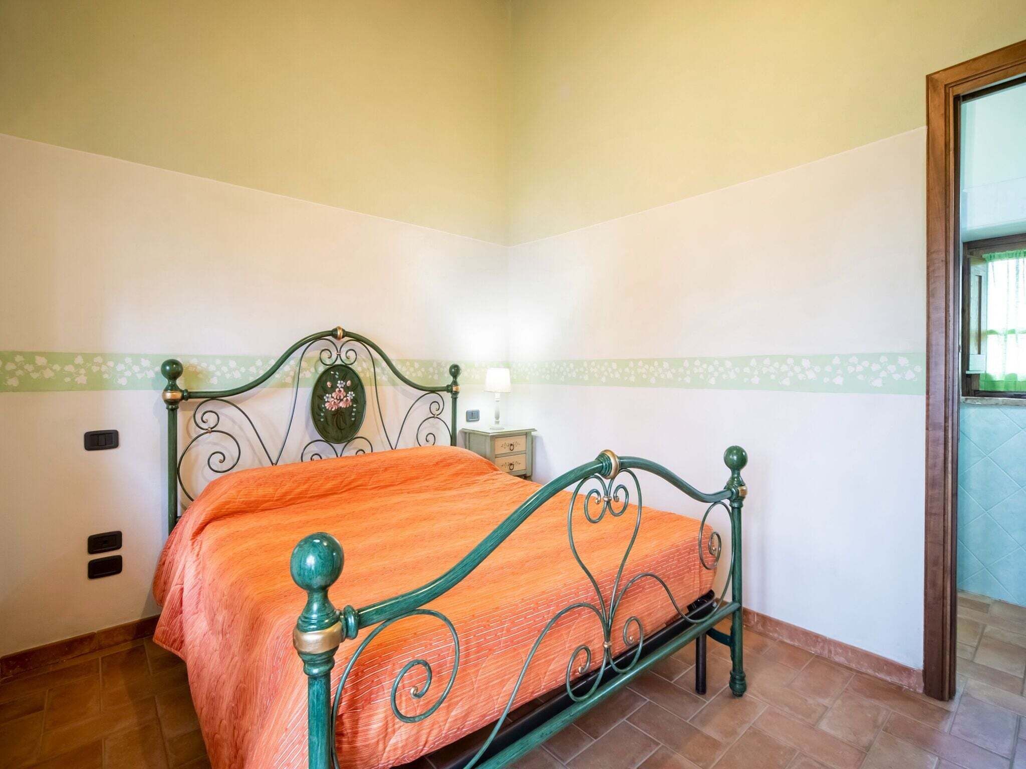 A room with a bed, a nightstand, and a wall-mounted light.
