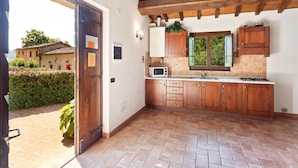 Una cocina con armarios de madera, microondas y ventana con vistas a zonas verdes.