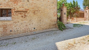 Un edificio de piedra con un cartel que indica una granja y vistas a una zona vallada con árboles.