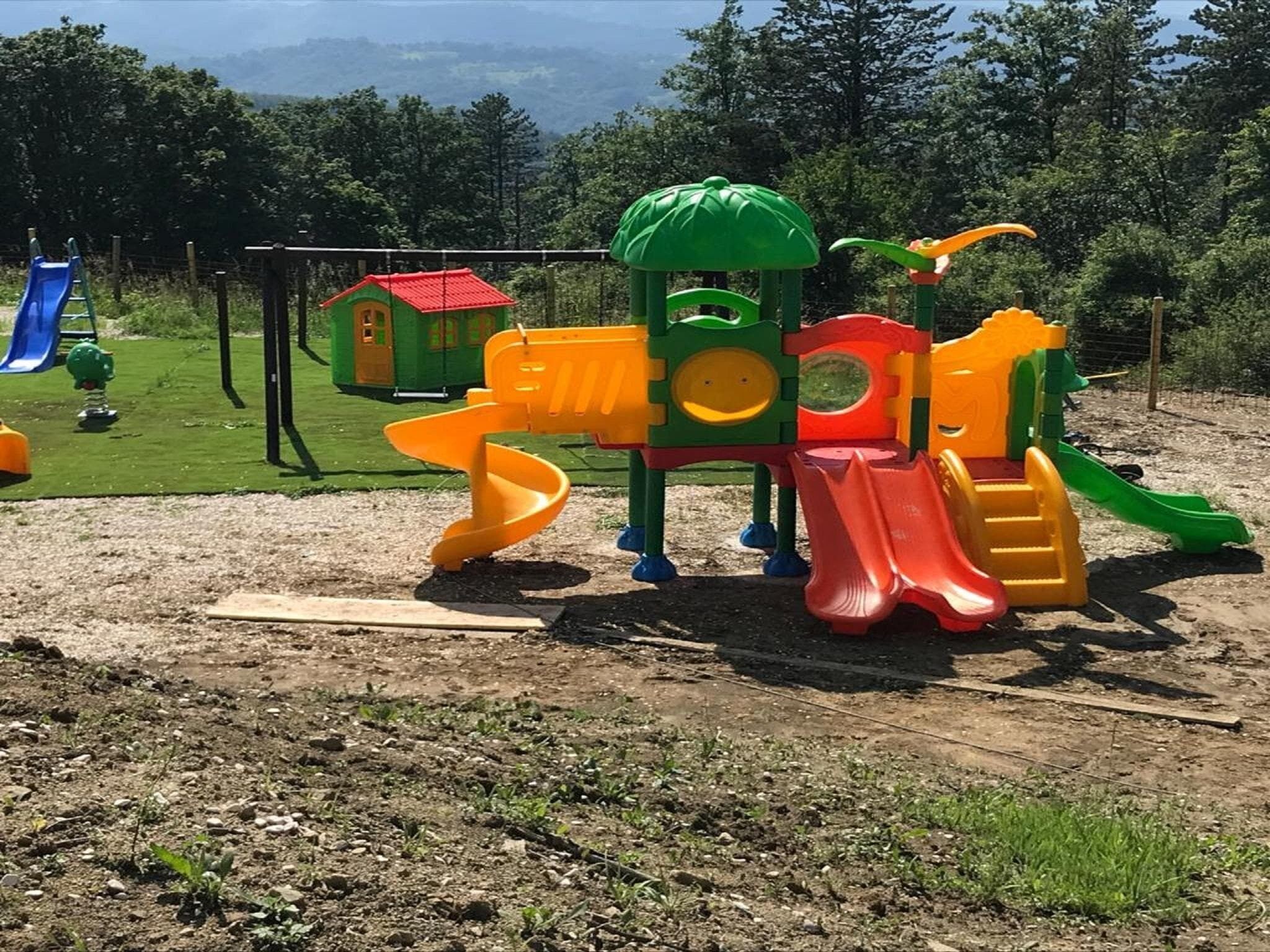 Un parque infantil con tobogán, estructuras de escalada y una casita.