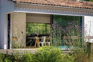 Una casa moderna con patio, mobiliario exterior y piscina.
