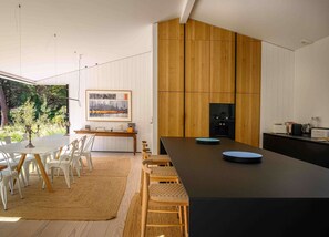 Una cucina moderna con un'isola grande, mobili bianchi e vista sul verde circostante.