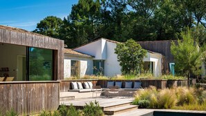 Une maison moderne dotée d’une terrasse en bois, d’un espace salon extérieur et d’une piscine.