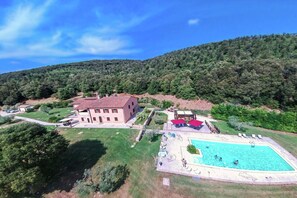 A villa with a swimming pool, surrounded by lush greenery and hills.