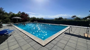 A rectangular swimming pool with clear blue water, surrounded by a tiled deck.