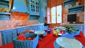 A kitchen with blue cabinets, a red tablecloth, and various kitchen items.