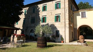 A stone building with green shutters, a courtyard with outdoor seating, and a barrel. - Farmhouse in Umbria near Lake Trasimeno (Gualdo Cattaneo)