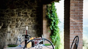 Une table dressée à l’extérieur, avec une bouteille de vin, des verres et une assiette de nourriture.